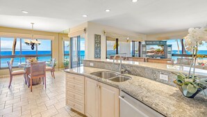 Una cocina moderna con una isla grande, un comedor con vista al océano y una sala de estar con vista a la playa.