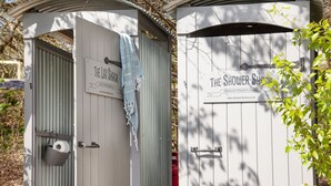Two portable shower stalls with signs indicating their purpose.