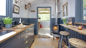 A kitchen with a wooden countertop, a sink, a stove, and a view to the outside.