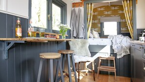 A kitchen with wooden stools, a bar counter, and a window with curtains.