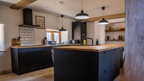 A modern kitchen with black cabinetry, a wooden countertop, and pendant lighting. - Keepers Lodge Knowstone (Knowstone)