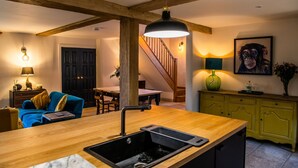 A kitchen with a wooden countertop, a sink, and a dining area with a blue sofa. - Keepers Lodge Knowstone (Knowstone)