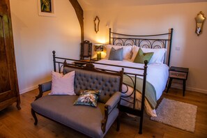A bedroom with a four-poster bed, a bench with cushions, a bedside table, and a wall-mounted mirror. - Keepers Lodge Knowstone (Knowstone)