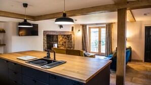 A kitchen with a wooden island, built-in cabinets, and a stone fireplace. - Keepers Lodge Knowstone (Knowstone)