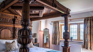 A four-poster bed with intricate carvings, a large mirror, and a window with patterned curtains. - Keepers Lodge Knowstone (Knowstone)