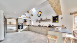 Un'ampia cucina con un'isola grande, illuminazione a sospensione e un soffitto rustico.