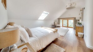 Una camera da letto con un lucernario, un letto, un comodino, una sedia e una finestra.