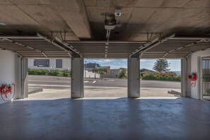 An empty garage with a concrete floor, metal beams, and a security camera. - Luxurious Beach Escape in Bloubergstrand (Cape Town)