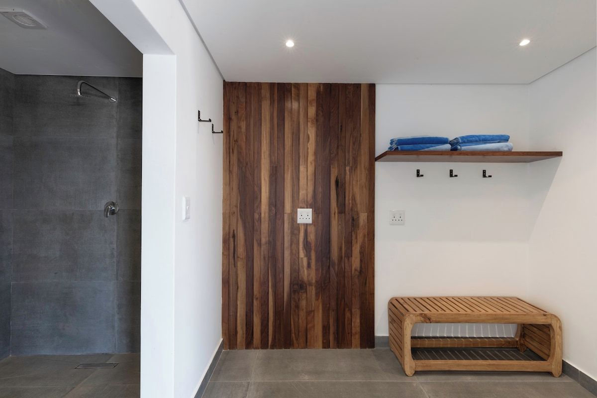Ein Badezimmer mit Dusche, einer Holzwand, einem Ablagefach mit gefalteten Handtüchern und einer Bank.