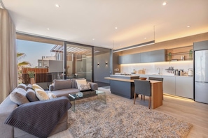 A modern living room with a sofa, coffee table, and a view of the outside.