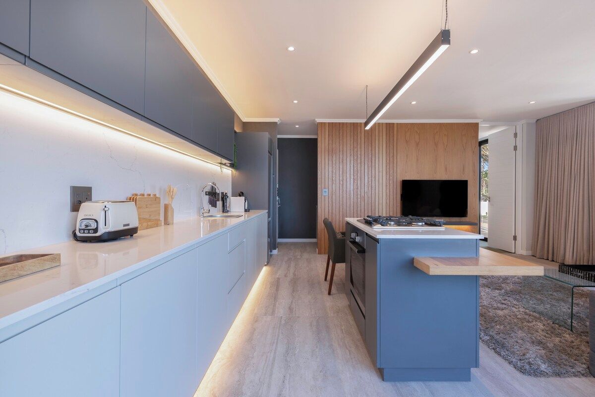 A modern kitchen with a central island, built-in appliances, and a flat-screen TV.