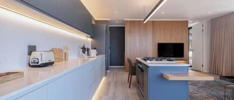 A modern kitchen with a central island, built-in appliances, and a flat-screen TV.