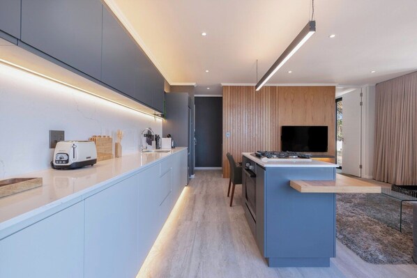 A modern kitchen with a central island, built-in appliances, and a flat-screen TV.