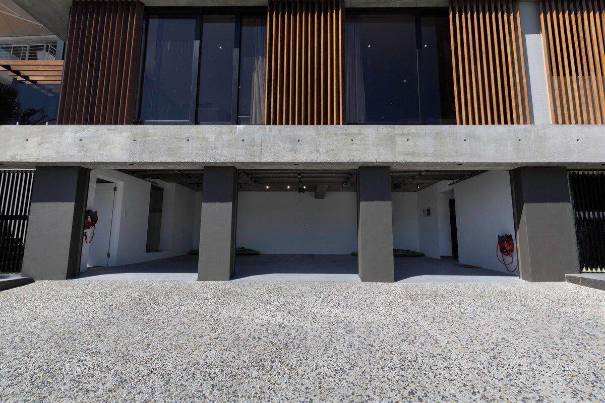 A modern building with a concrete facade, large windows, and a covered entrance area.