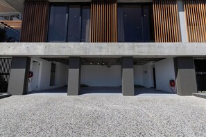 A modern building with a concrete facade, large windows, and a covered entrance area. - Luxurious Beach Escape in Bloubergstrand (Cape Town)