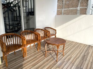 A corner room with a wooden table and four chairs, a glass door, and a brick wall. - Hotel O Penginapan Musafir Syariah Near Paramount Woman & Childern's Hospital (Makassar)