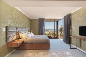 A bedroom with a large bed, a nightstand, a TV, and a view of the sea. - State of the Art Bloubergstrand Breakaway! (Cape Town)
