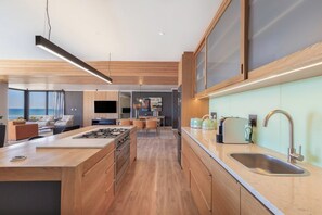 A modern kitchen with a central island, a built-in oven, and a large window overlooking the sea. - State of the Art Bloubergstrand Breakaway! (Cape Town)