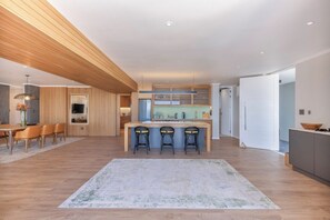 A modern kitchen with a central island, bar stools, and a dining area with a table and chairs.
