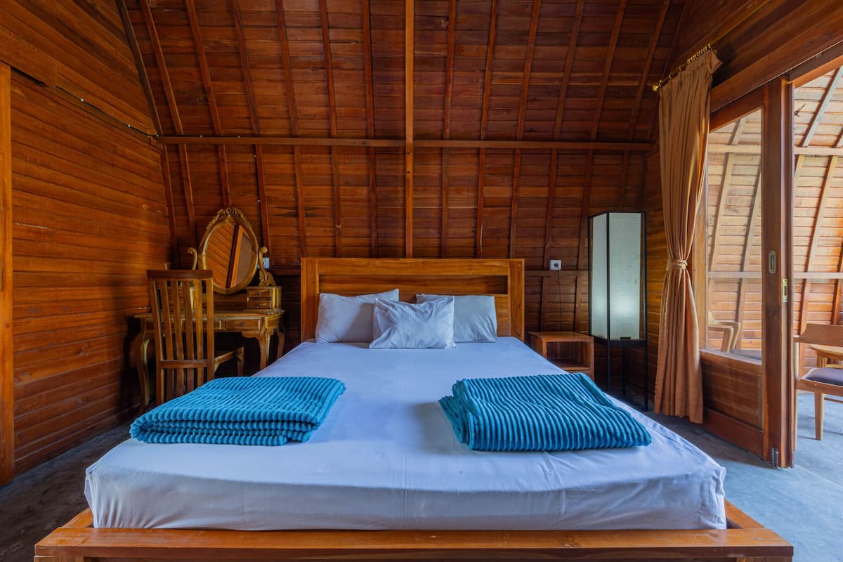 Een houten kamer met een bed, een houten bureau, een stoel en een spiegel.