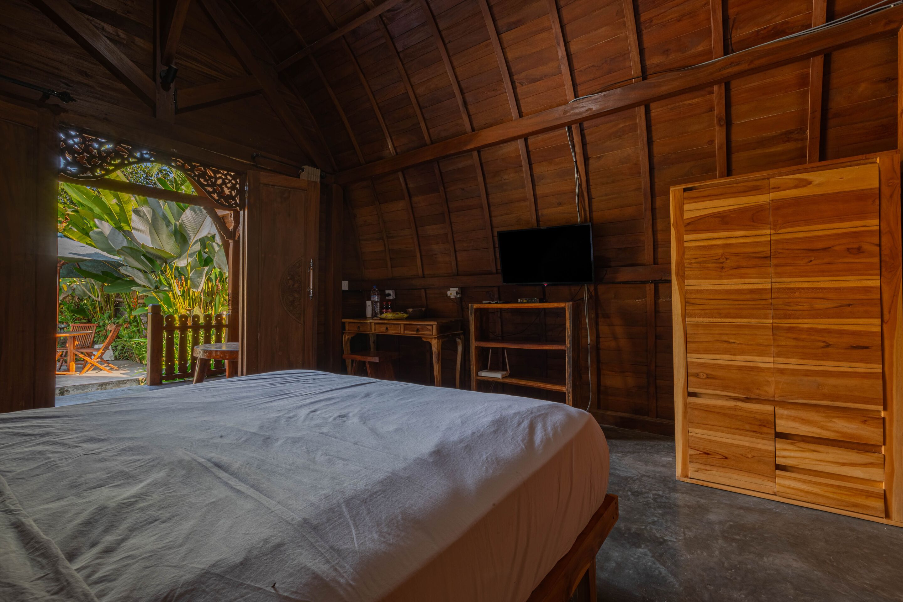 Une pièce en bois avec un lit, un bureau, une chaise et un téléviseur.
