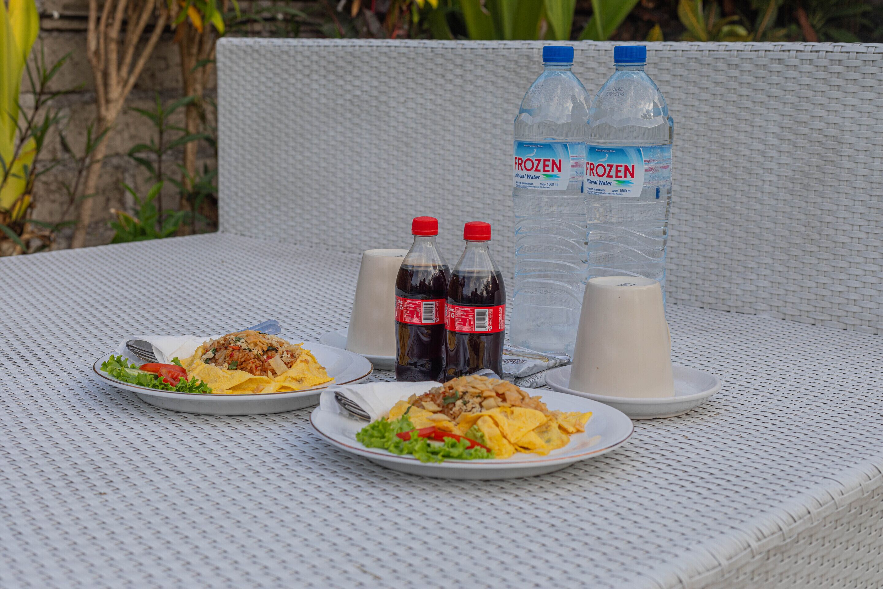 Une table avec deux assiettes de nourriture, deux bouteilles d’eau et deux tasses.
