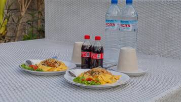 Une table avec deux assiettes de nourriture, deux bouteilles d’eau et deux tasses.