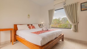 A bedroom with a wooden bed, a bedside table, a window with curtains, and an air conditioning unit. - Lahi Villa  (Penida Island)
