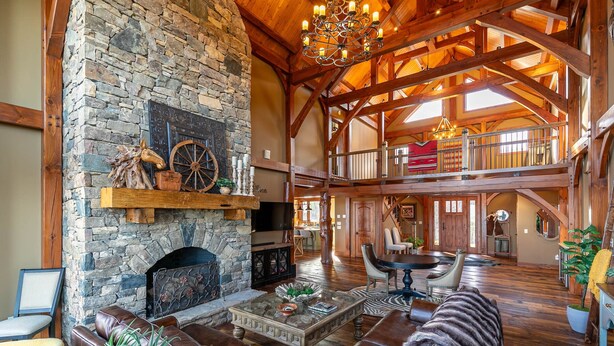 Un intérieur spacieux agrémenté d’une cheminée en pierre, de sièges en cuir et d’un haut plafond en bois.