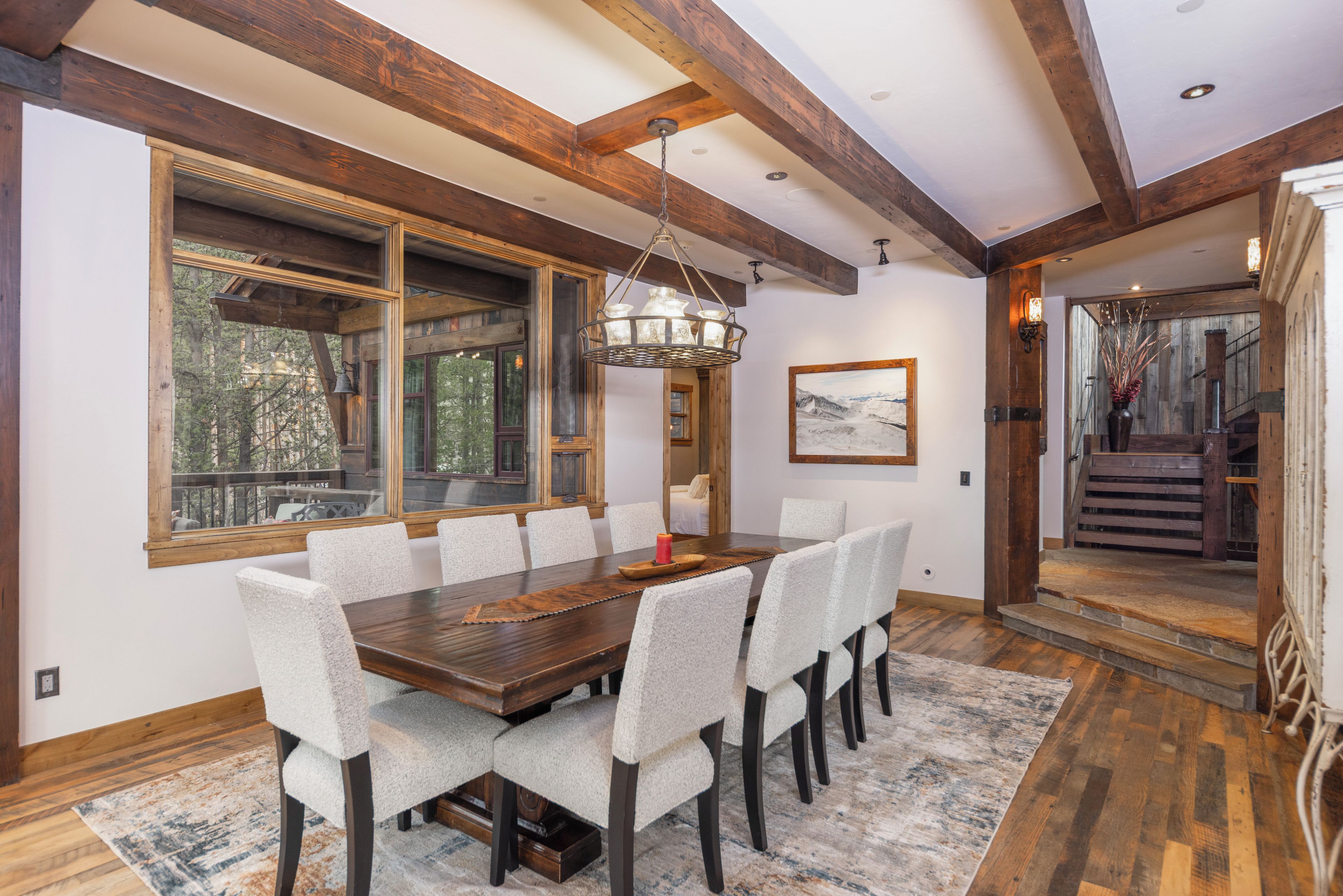 A dining room with a large wooden table, six chairs, and a chandelier.