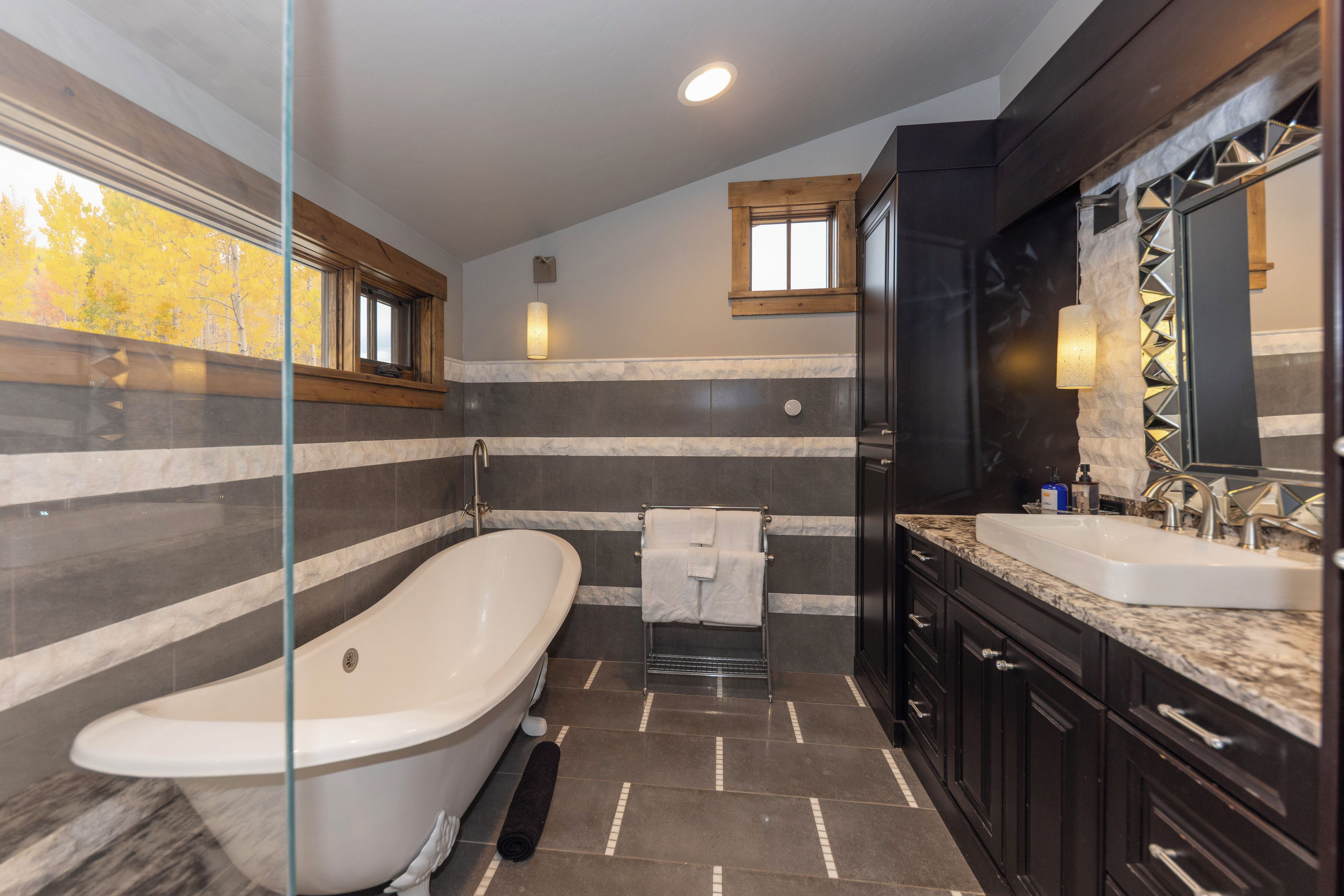 Une salle de bain moderne avec une baignoire sur pieds, un meuble-lavabo avec miroir et un espace douche.