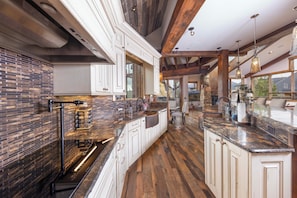 A spacious kitchen with high ceilings, exposed wooden beams, and a stone accent wall. - The Apex of Ski-In Ski-out Estates. Walk to Restaurants, Theater, Hot Tub, Game Tables! (Breckenridge)