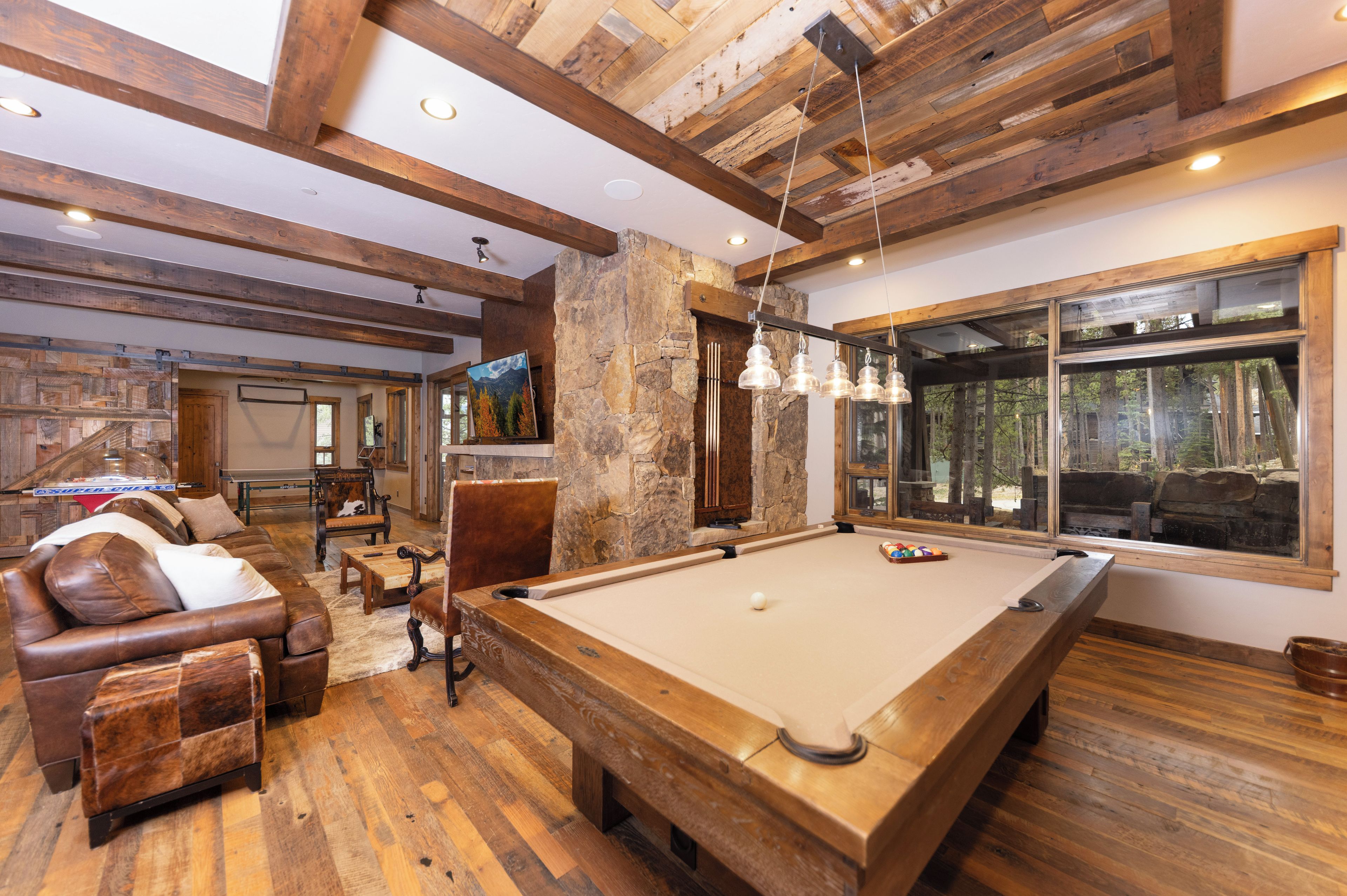 A spacious room with a pool table, leather seating, and a stone accent wall.