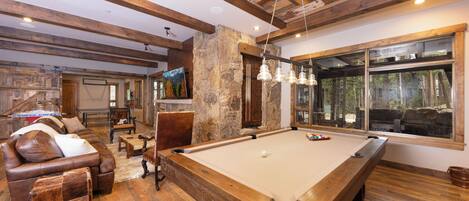 A spacious room with a pool table, leather seating, and a stone accent wall.