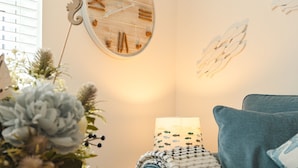 A cozy room with a blue sofa, a wall clock, and a lamp.