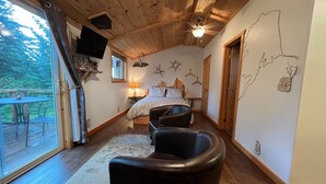 Une chambre avec un lit, une chaise, un ventilateur de plafond et une vue sur l’extérieur.