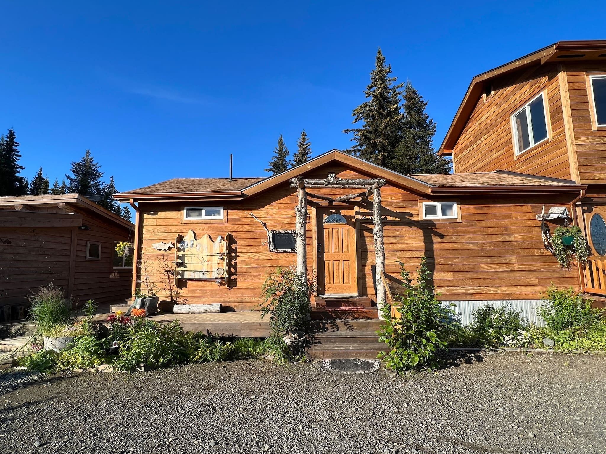 A wooden cabin with a front porch, a wooden door, and a small window.