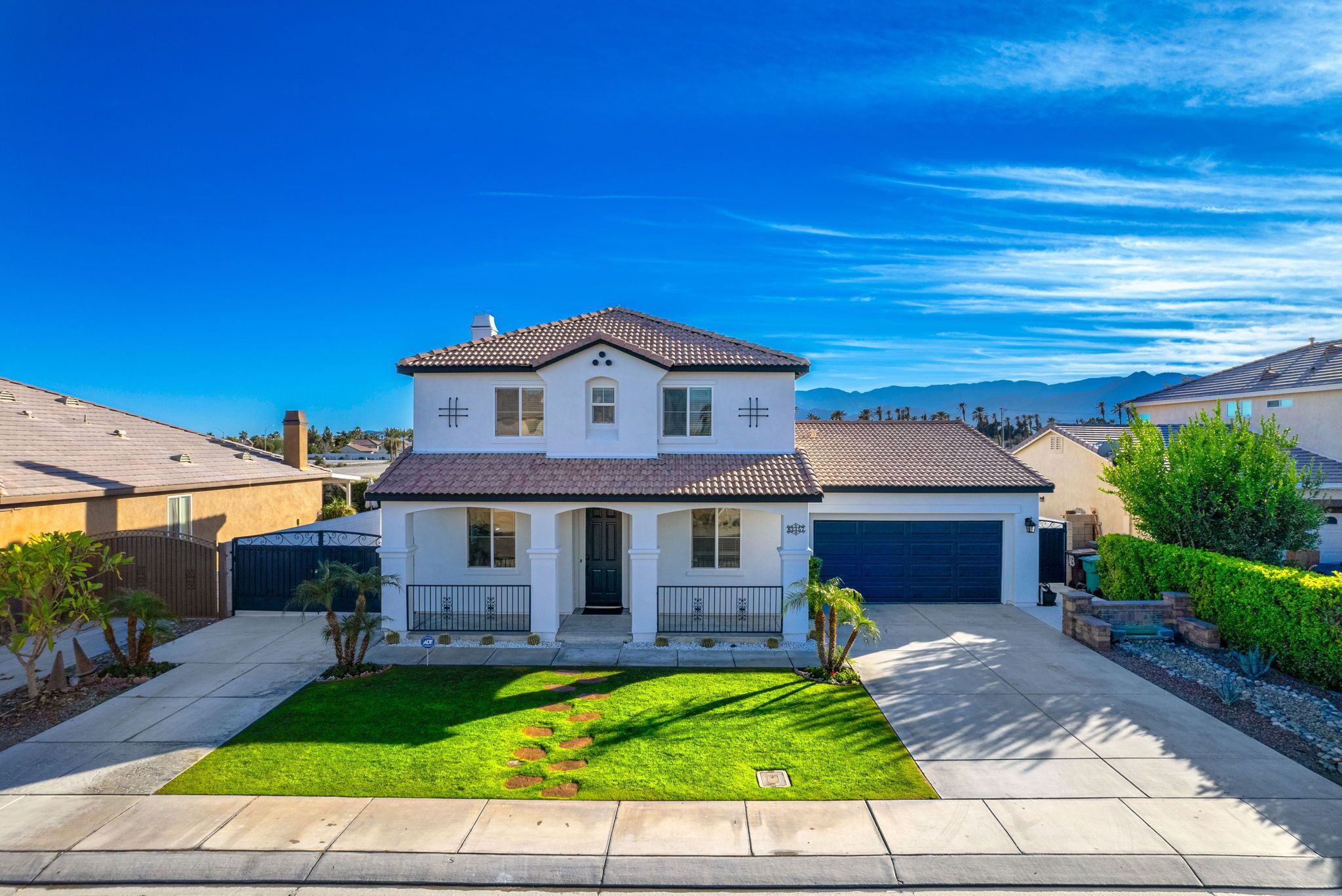 A two-story house with a front porch, a garage, and a well-maintained lawn.