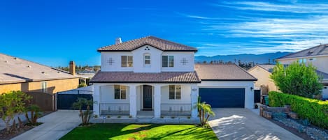 A two-story house with a front porch, a garage, and a well-maintained lawn.