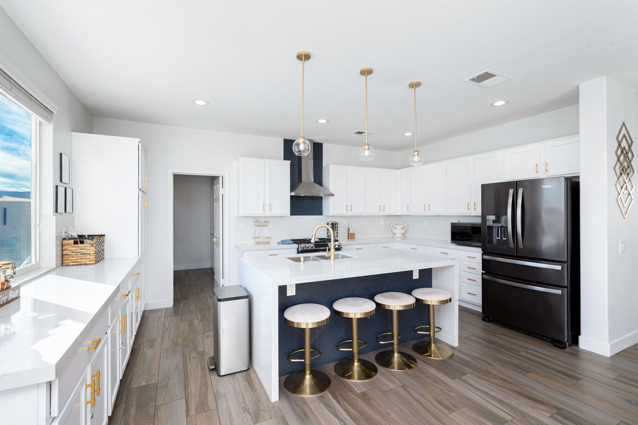 A modern kitchen with white cabinets, a black refrigerator, and a central island with stools.