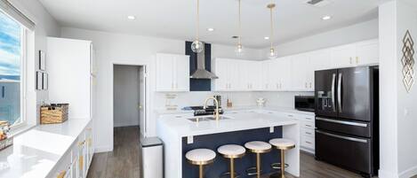 A modern kitchen with white cabinets, a black refrigerator, and a central island with stools.
