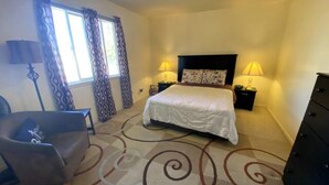 Habitació d'hotel amb un llit gran, dues làmpades de nit, una cadira i un aparador.