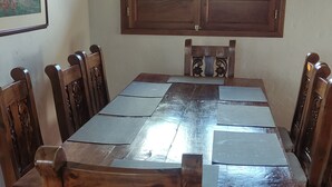 Un comedor con una gran mesa de madera y sillas, una ventana con vistas a la vegetación y un cuadro en la pared.