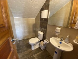 Un baño con inodoro, lavamanos y secamanos.