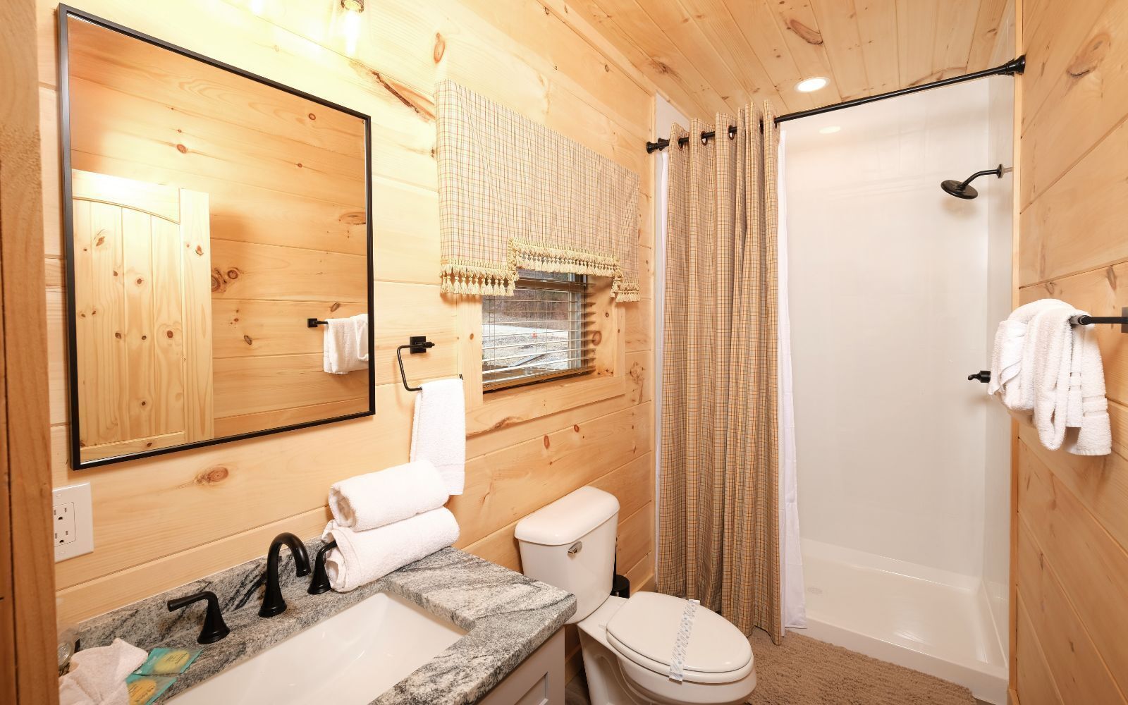 A wooden cabin bathroom with a sink, toilet, and shower.