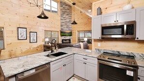 A modern kitchen with granite countertops, stainless steel appliances, and wooden paneling.