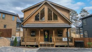 A two-story log cabin with a front porch, a large window, and a sign that reads "Cabin You."