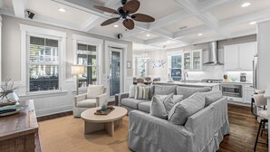 A spacious living room with a grey sofa, a coffee table, and a ceiling fan. - Perfect Pitch: Your Serene NatureWalk Haven - 6 Seater Golf Cart (Santa Rosa Beach)