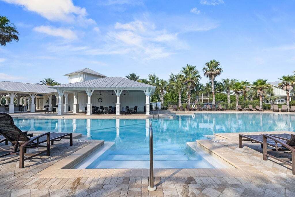 A swimming pool with lounge chairs and a covered seating area.