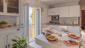 A compact kitchen with white cabinets, a microwave, and a dining area with a table set for two.
